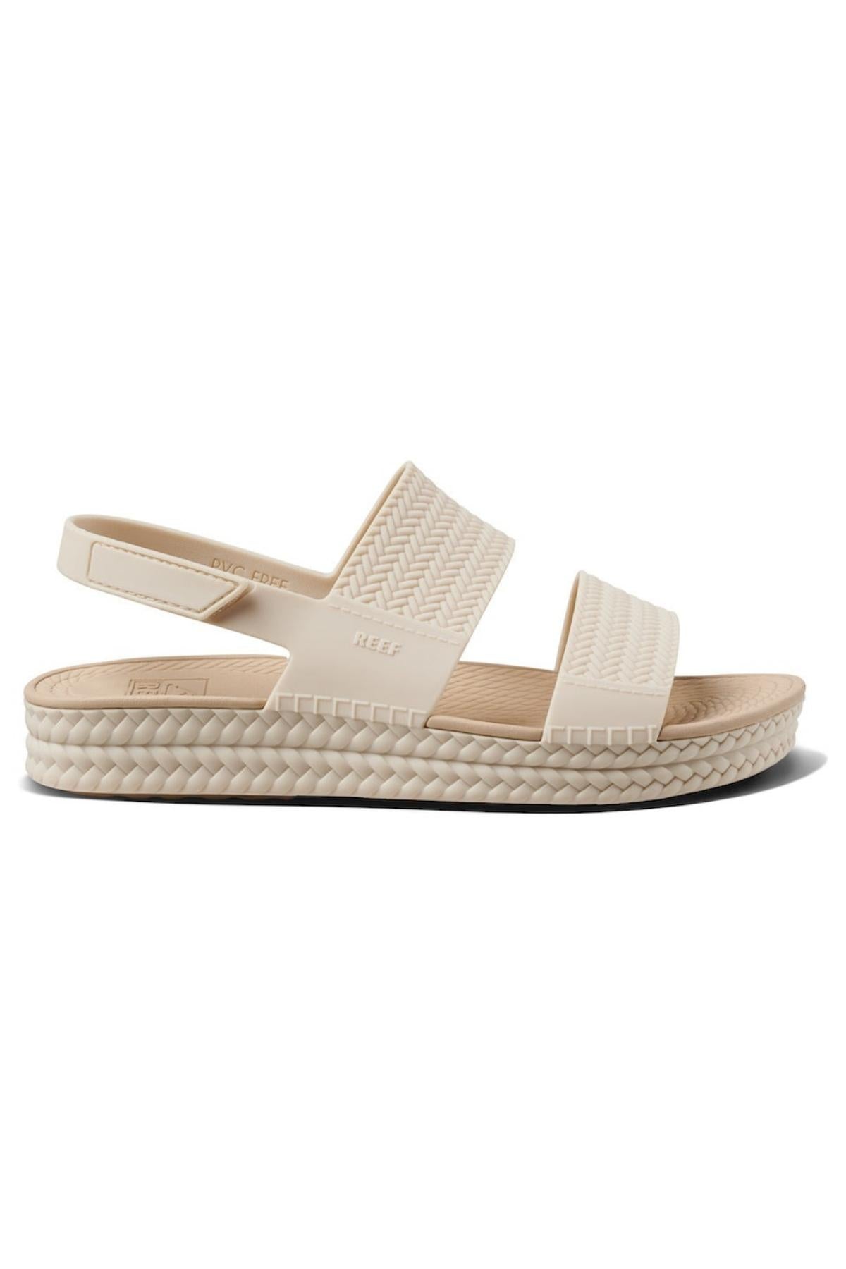 The REEF Water Vista Duo is a beige sandal featuring a textured sole, two wide woven-style straps, an open heel with adjustable Velcro backstraps, and a dual density lightweight EVA footbed for enhanced comfort.