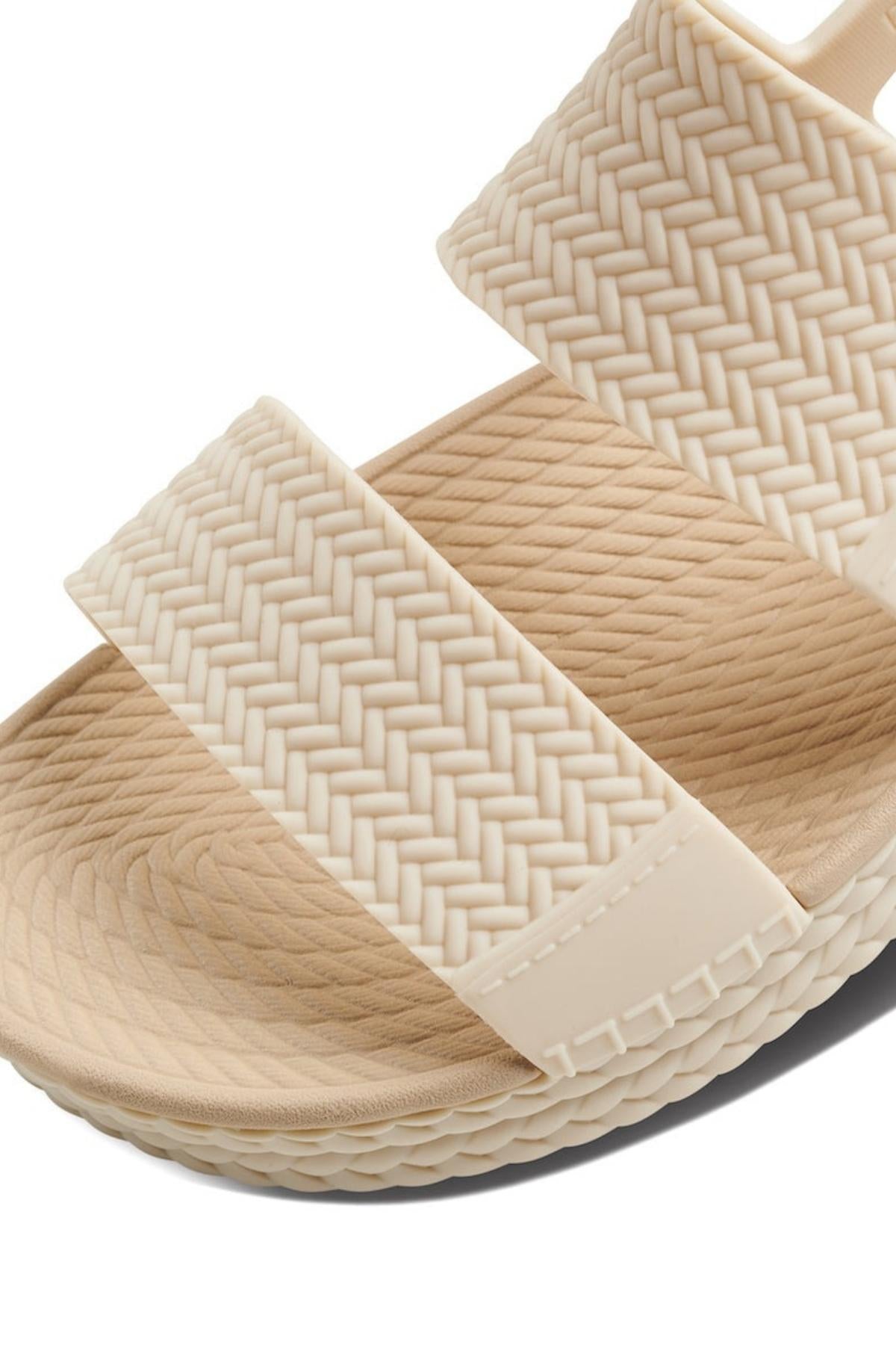 Close-up of the REEF Water Vista Duo sandal in beige, showing two wide, textured straps with a woven pattern. Features a contoured dual-density EVA footbed and adjustable Velcro backstraps for comfort and secure fit.