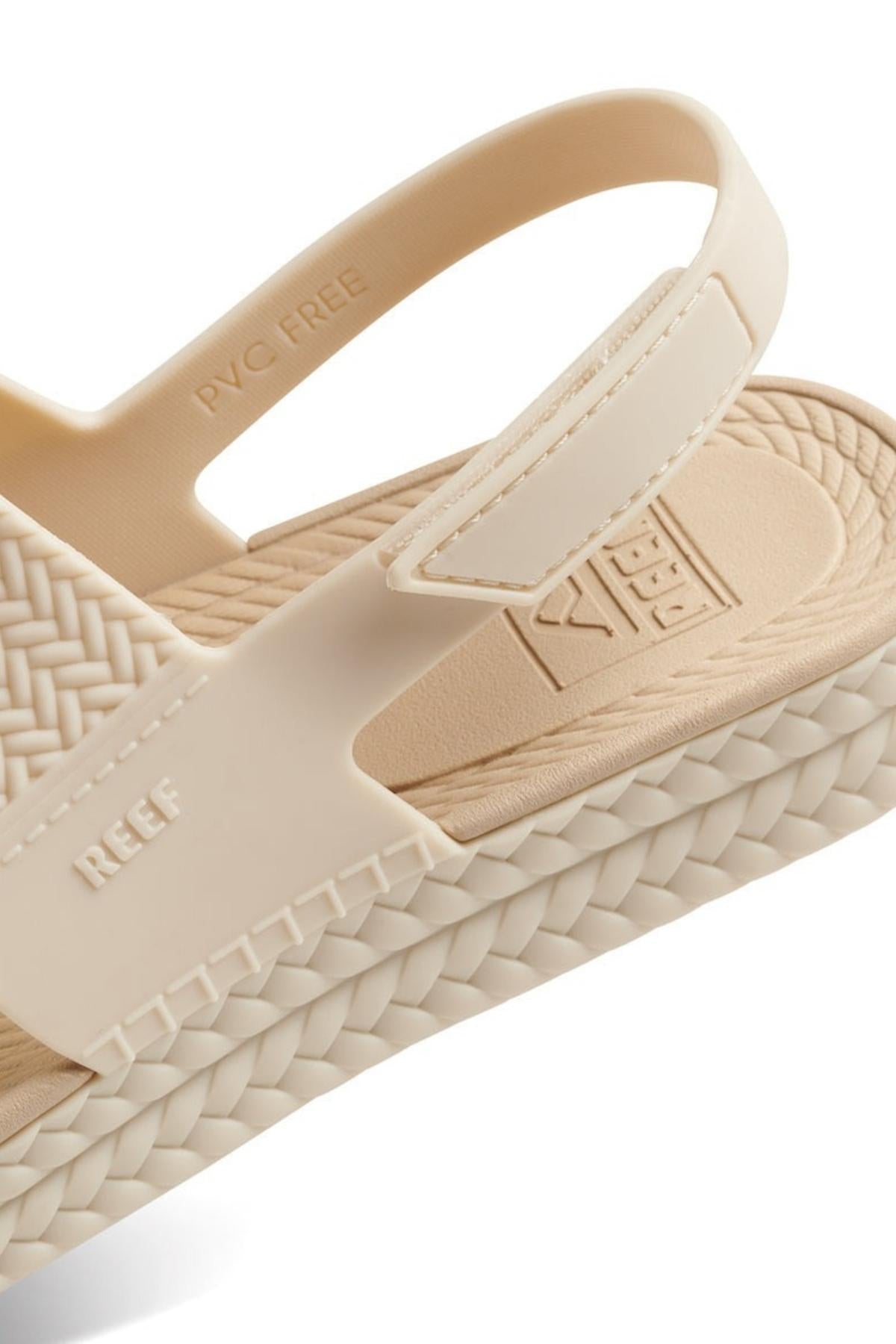 Close-up of the REEF Water Vista Duo sandal, featuring a stylish woven design, textured sole, adjustable velcro backstraps, βPVC FREEβ label, REEF branding on the dual density lightweight EVA footbed.