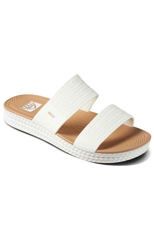 The REEF Water Vista Slide features two textured white straps over a tan dual-density EVA footbed and a white textured sole, shown at an angle against a simple background.