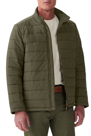 A person is wearing a durable polyester twill olive Patterson Creek Jacket by RM Williams with matching pants. The quilted puffer jacket, slightly open to reveal a white T-shirt underneath, stands out against the plain white background.