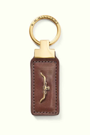 The RM Williams Angaston Key Fob is a brown leather keychain made from full-grain leather with gold accents and features a metal bull's head emblem. The circular keyring is inscribed with text and decorated with antique brass hardware, adding timeless elegance.
