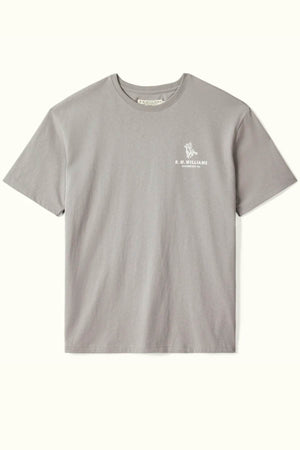 The RM Williams Banner T-Shirt is a gray, short-sleeved garment with a classic round neckline, made from breathable organic cotton for a relaxed fit. It showcases a small white heritage logo on the upper left side, featuring "R.M. WILLIAMS" accompanied by a graphic above the text, all set against a plain light background.