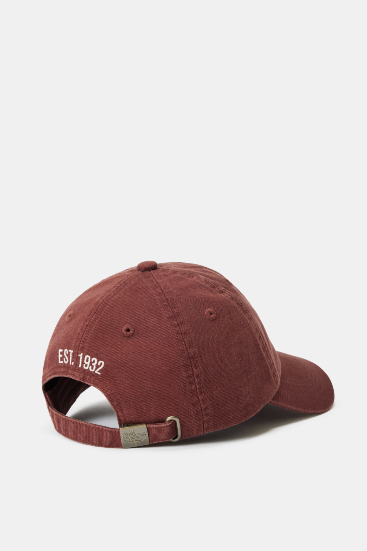 The RM Williams Branded Twill Cap, shown from the back in maroon, features a white "EST. 1932" embroidery above a metal buckle. Set against a plain white background, this classic cap highlights its signature embroidered logo and adjustable strap.