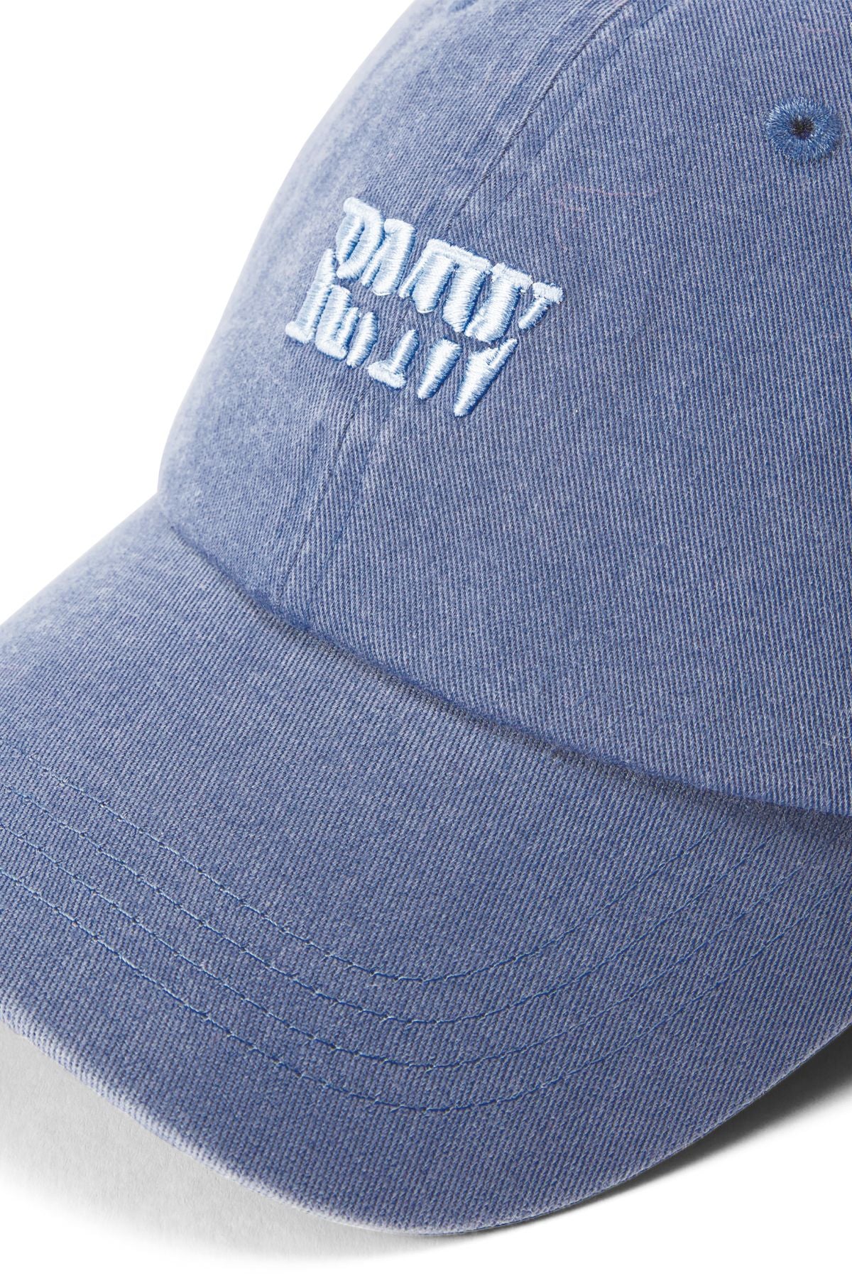 A close-up of the RM Williams Branded Twill Cap in blue organic cotton features white "palm" text embroidered upside down, a curved brim, visible stitching, and an adjustable strap.