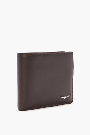 The RM Williams City Slim Bi-Fold, crafted from full grain brown leather and adorned with a small metallic bull emblem in the corner, stands upright against a plain white background. Its elegant design features multiple card slots for convenience.