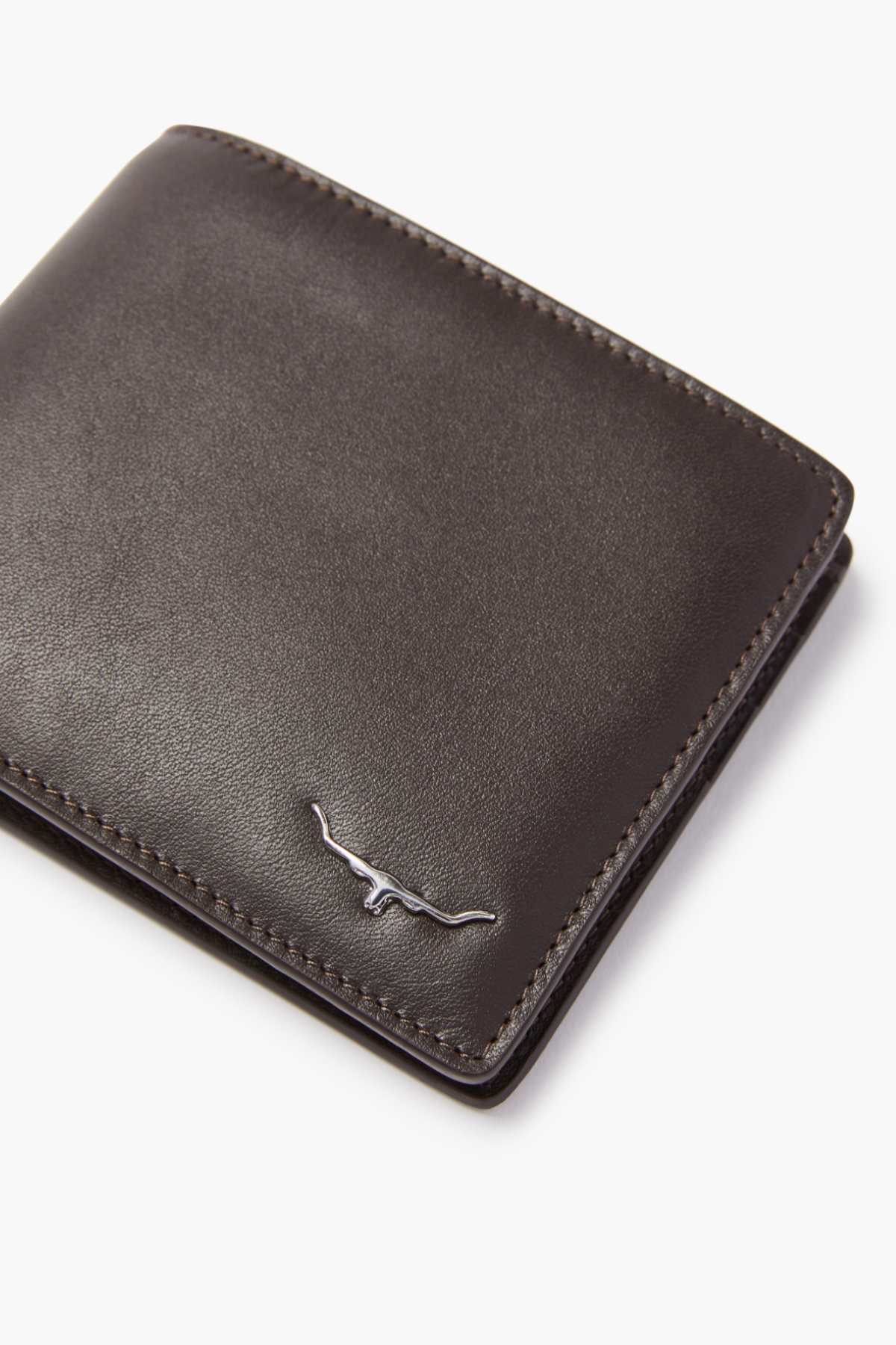 A close-up of the RM Williams City Slim Bi-Fold wallet, crafted from dark brown full grain leather with a silver longhorn logo in the corner. It features multiple card slots, all set against a pristine white background.