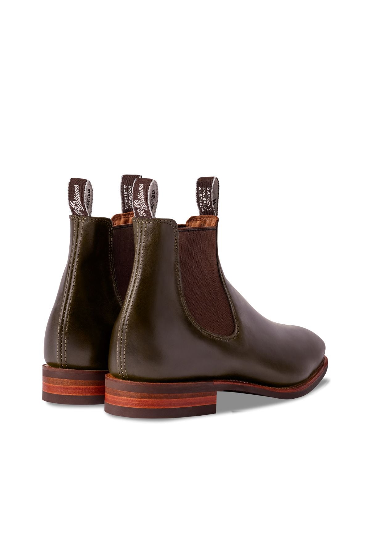 The RM Williams Comfort Craftsman Boot is an olive green pull-up leather Chelsea boot with brown elastic side panels, brown pull tabs, and wooden soles, shown from the back and side.