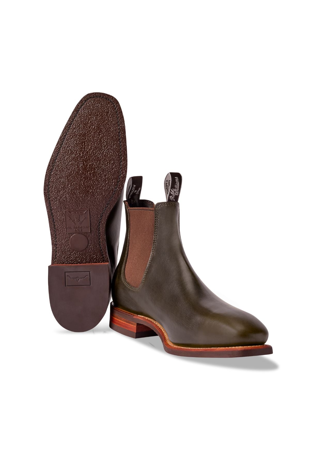 A pair of brown RM Williams Comfort Craftsman Boots in classic Chelsea style with elastic side panels and pull tabs—one boot upright, the other shows the textured sole. Crafted in Australia for exceptional quality and comfort.