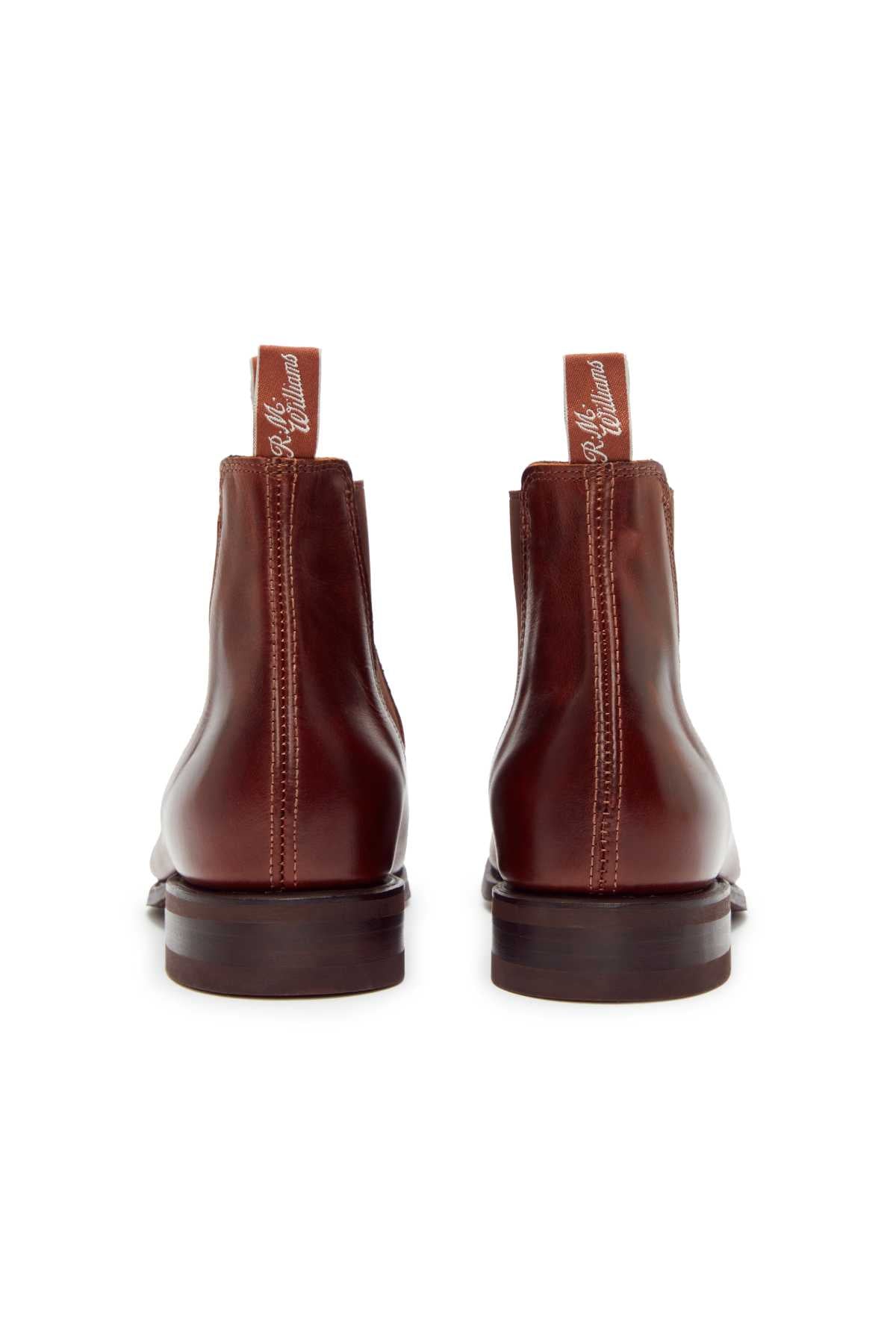 The RM Williams Comfort Craftsman Boot in brown yearling leather is shown from the back, featuring pull tabs with white script, low stacked heels, and a durable rubber welt sole.