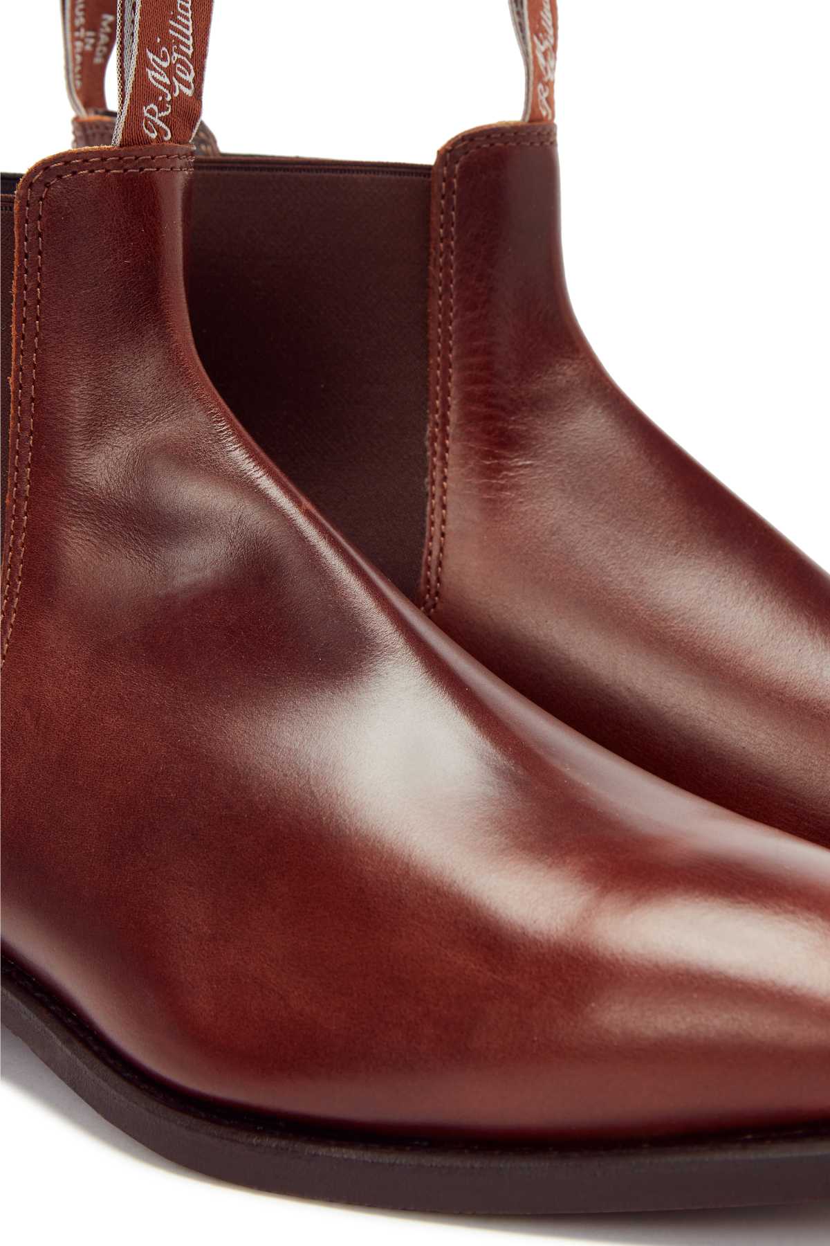 Close-up view of the RM Williams Comfort Craftsman Boot—a pair of polished brown Chelsea boots, crafted from yearling leather with pull tabs and signature fine craftsmanship.