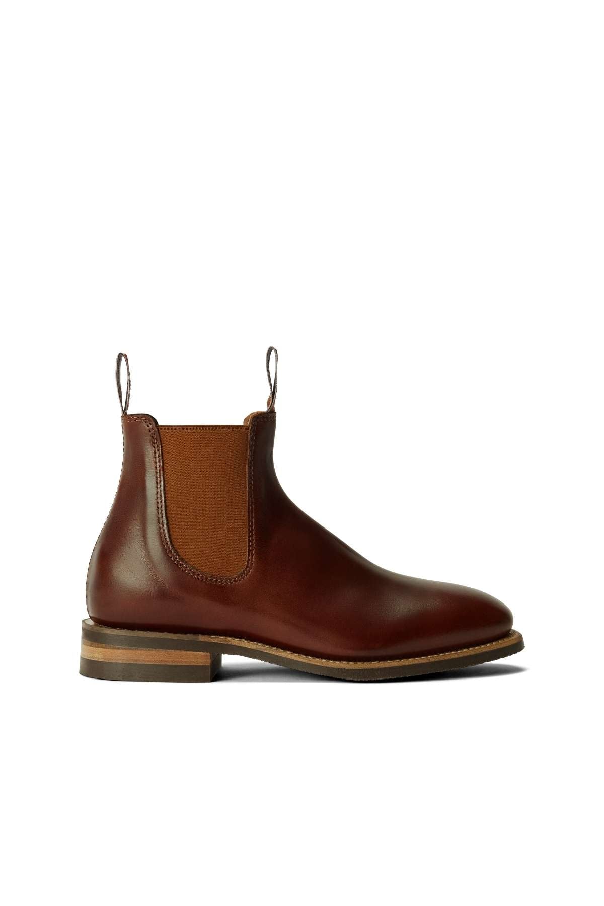 The RM Williams Comfort Craftsman Boot is a brown leather Chelsea boot with elastic side panels, front and back pull tabs, and a low stacked wooden heel, shown in profile on a white background.