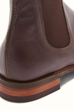 Close-up of the heel of the RM Williams Comfort Kangaroo Craftsman Boot, made from premium brown kangaroo leather with visible stitching and a layered wooden sole. On the right side of the shoe, there's a dark brown elastic panel. The image captures the texture and craftsmanship of this footwear, proudly made in Australia.