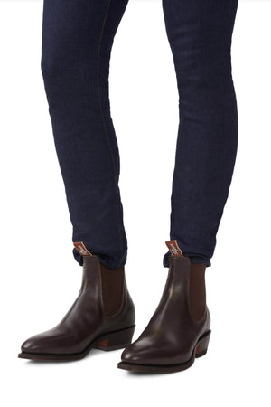 The individual sports the RM Williams Comfort Lady Yearling Rubber Sole Boots in a sleek dark brown leather with elastic sides and pairs them expertly with dark jeans.