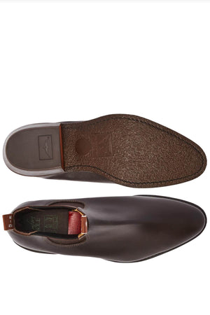 A pair of RM Williams Comfort Lady Yearling Rubber Sole Boots, showcased from the top and sole views. The top view emphasizes a sleek brown leather finish, while the outsole reveals a textured pattern. A red pull tab at the heel brings to mind the classic Yearling boot style.