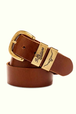 A brown RM Williams Drover Belt, made in Australia, features a gold-colored rectangular buckle engraved with the brand name "Rile Cattleman" and a cattle emblem. The pull-up leather belt is coiled, showcasing its smooth texture and polished finish.