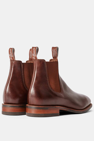 The RM Williams Dynamic Flex Craftsman Boot is a handcrafted leather Chelsea boot with elastic side panels and pull tabs. It features a smooth finish, spotlighting layered wooden and rubber soles with slight heels, embodying elegance.