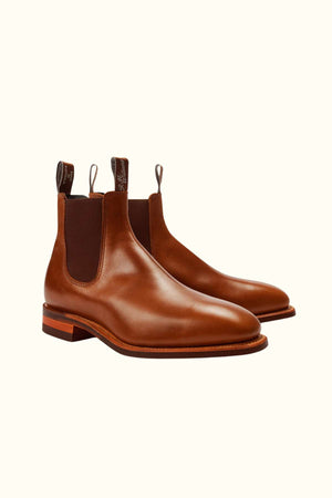 The RM Williams Dynamic Flex Craftsman Boot is a brown yearling leather Chelsea boot with elastic side panels, front and back pull tabs, a low heel, and Dynamic Flex technology, shown on a light background.