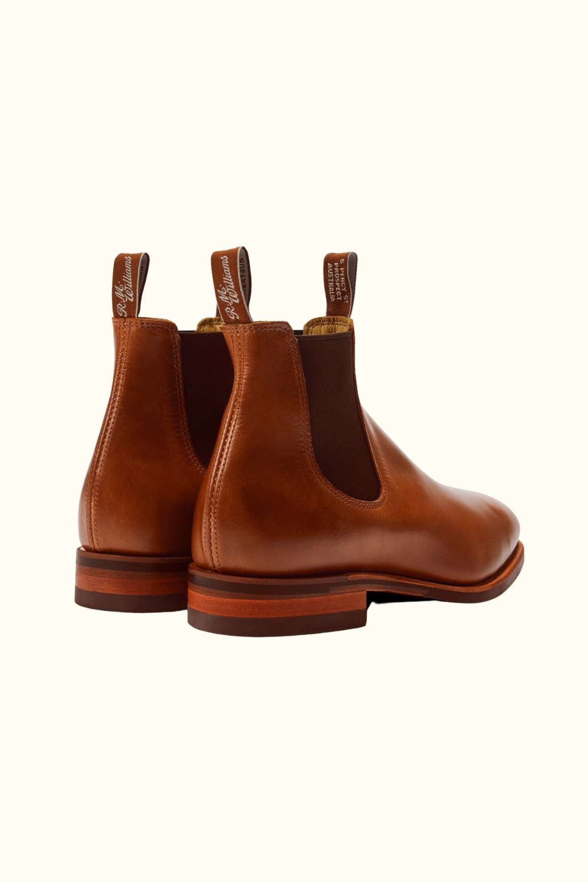 The RM Williams Dynamic Flex Craftsman Boot is a brown leather yearling Chelsea boot with dark elastic side panels and back pull tabs, shown from the rear and side on a plain light background.