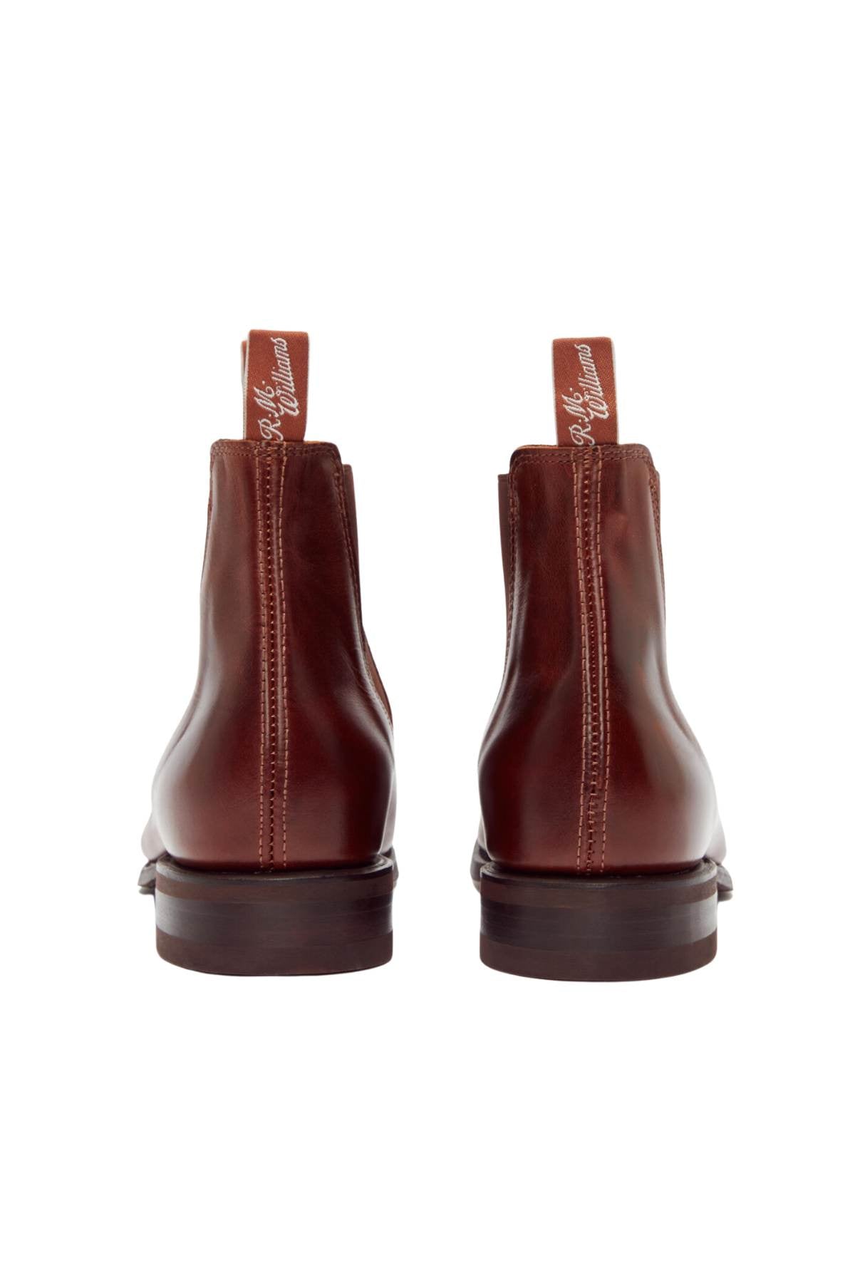A pair of RM Williams Dynamic Flex Craftsman boots in brown yearling leather, showcasing a polished finish from the back view. The boots are equipped with pull tabs at the top, which display text. They boast a smooth surface and distinct stitching along the sides and heel.