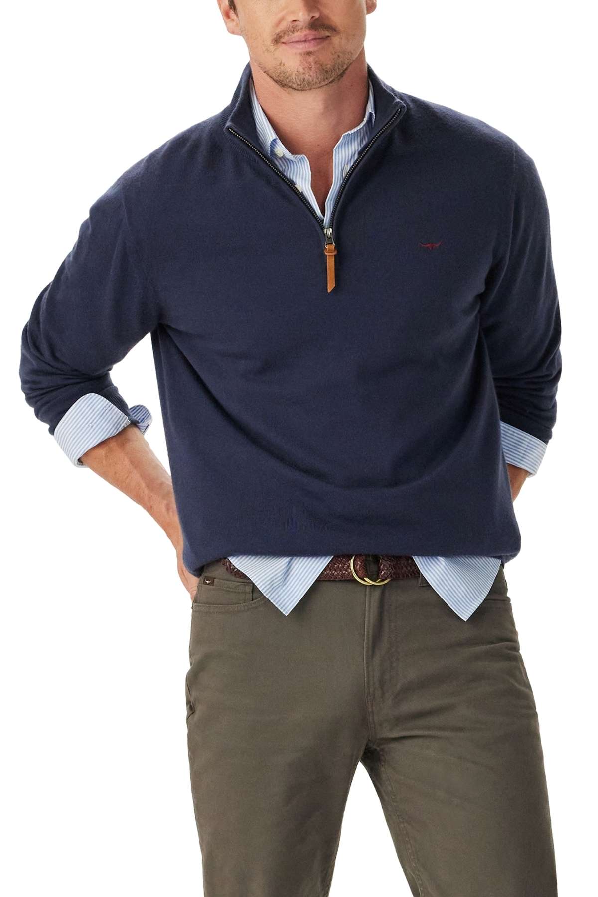 A man poses with one hand in his pocket, wearing the RM Williams Ernest Merino 1/4 Zip Knit in navy over a light blue shirt, paired with olive green pants and a brown braided belt. His face is partially cropped out of the frame.