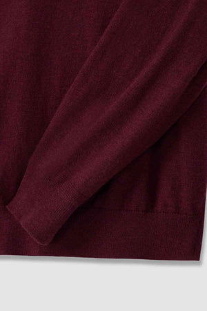 Close-up of an RM Williams Ernest Sweater in burgundy merino wool. The fine gauge fabric is soft and cozy with ribbed wrist cuffs. Its rich color implies warmth and comfort, perfect for a quarter zip sweater.