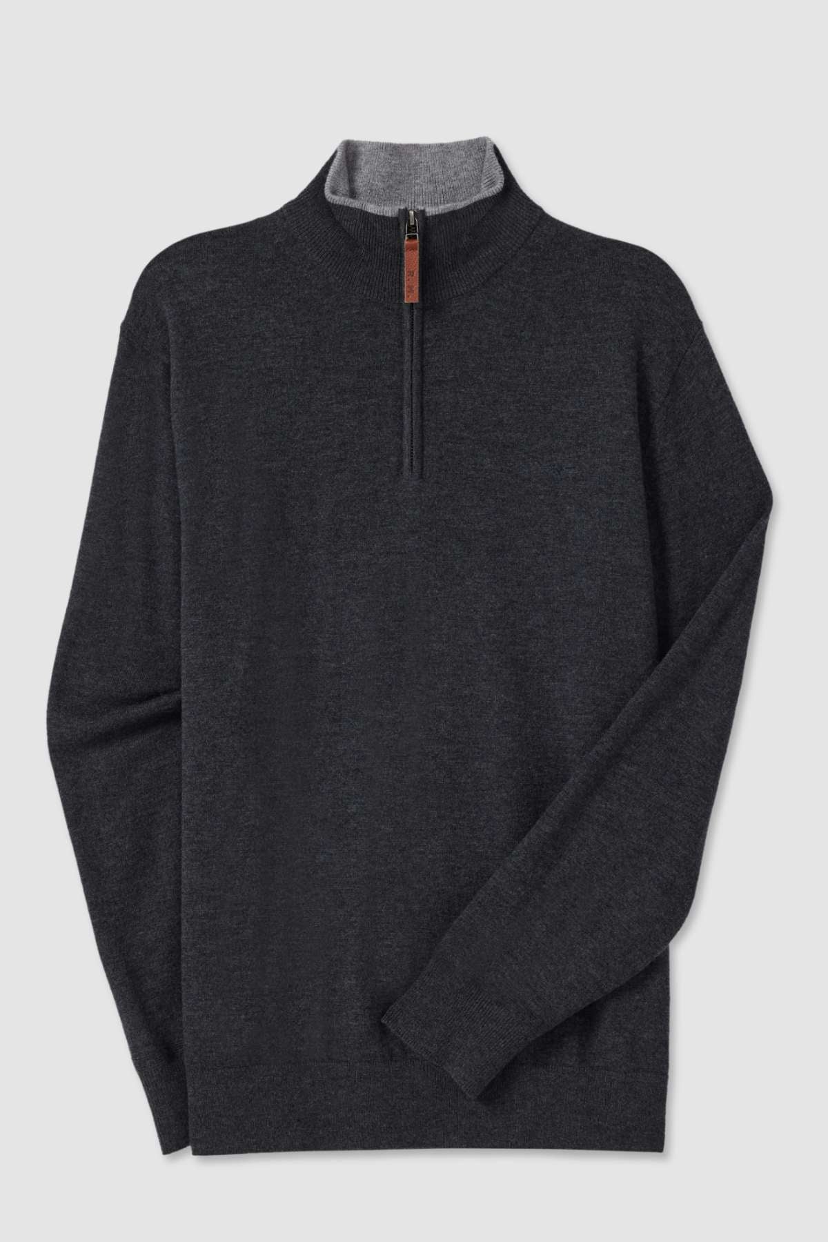 The RM Williams Ernest Sweater is a dark grey long-sleeve pullover with a quarter zip and a high collar, made from a fine gauge merino wool blend. The inner lining of the collar is light grey, providing a subtle contrast to the main body of the sweater, while the zipper features a small brown leather pull tab. The sweater is showcased against a plain white background.