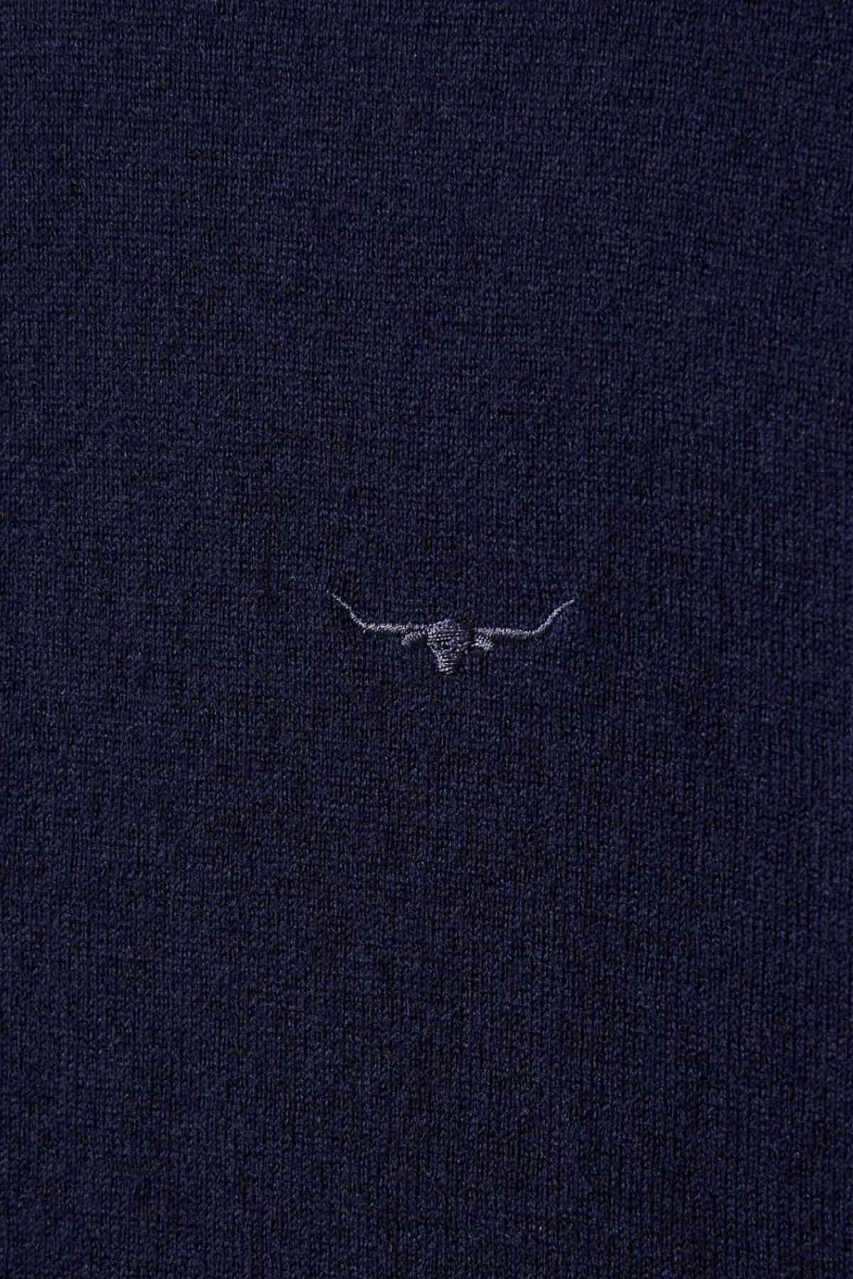 Close-up of the RM Williams Ernest Sweaterโs dark navy blue merino fabric, featuring a fine gauge knit and a small, subtle embroidered outline of a longhorn steer's head and horns at the center.