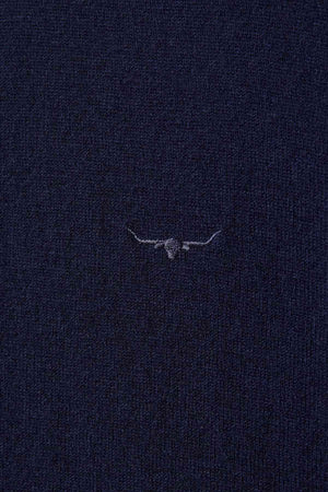 Close-up of the RM Williams Ernest Sweaterโs dark navy blue merino fabric, featuring a fine gauge knit and a small, subtle embroidered outline of a longhorn steer's head and horns at the center.