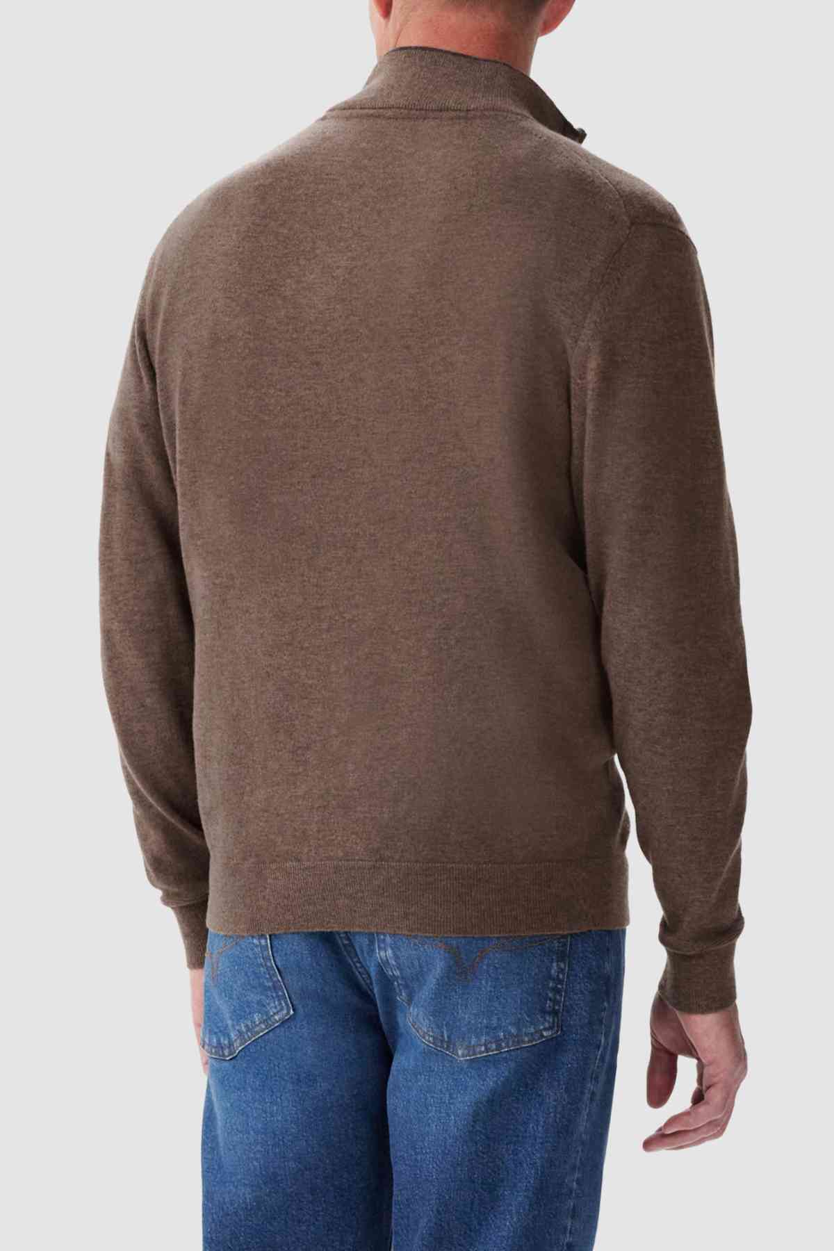 Rear view of a person wearing the RM Williams Ernest Sweater, along with blue jeans, standing against a plain light gray background.
