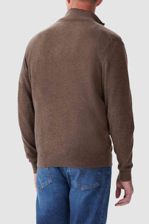 Rear view of a person wearing the RM Williams Ernest Sweater, along with blue jeans, standing against a plain light gray background.