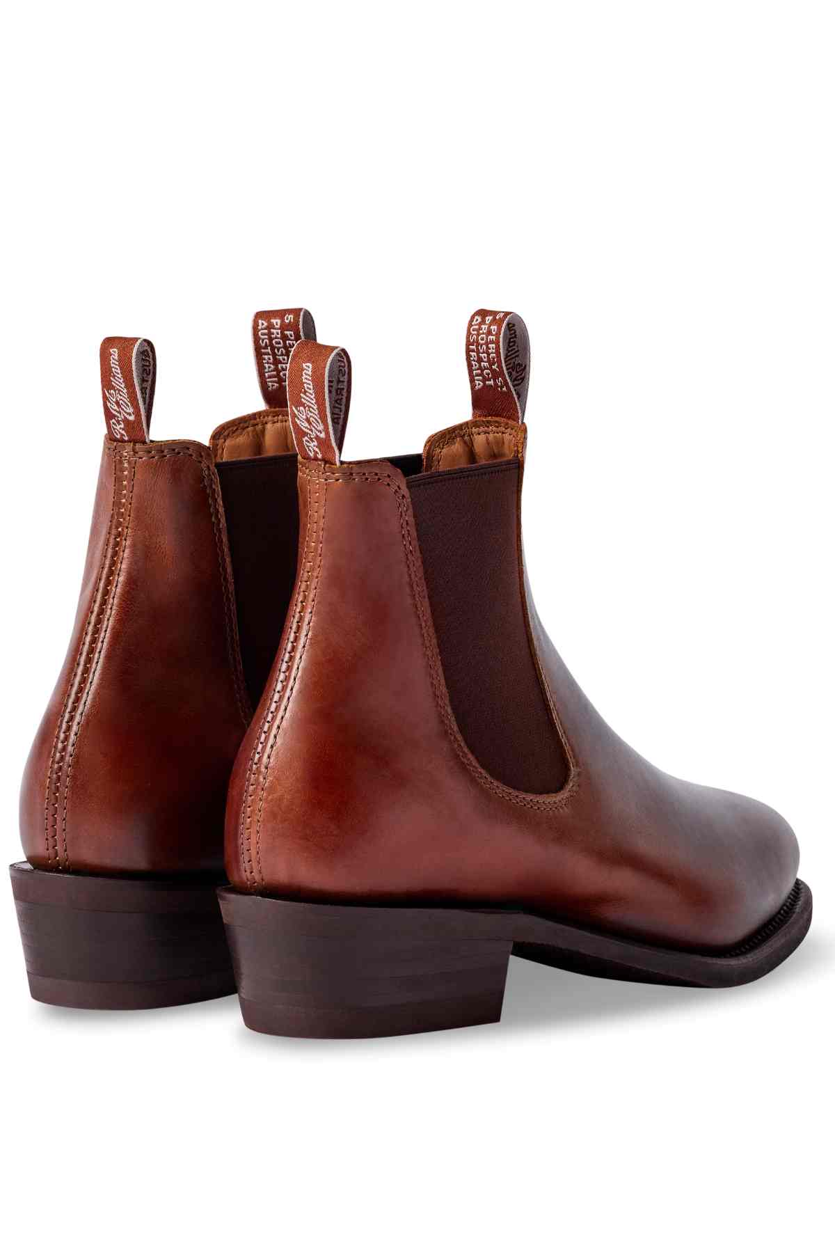 The RM Williams Lady Yearling Rubber Sole Boot features brown Spanish pull-up leather, dark elastic side panels, back pull tabs, a polished finish, and a low stacked heel, all set on a white background.