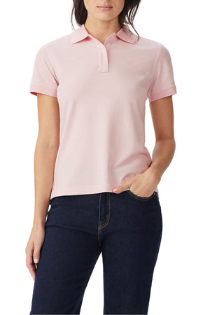 A person wearing a light pink RM Williams Margaret Polo and dark blue jeans, with one hand in their pocket, stands against a white background.