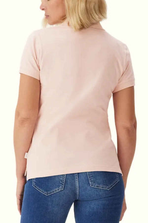 A person with blonde hair is seen from the back, wearing an RM Williams Margaret Polo in light pink pique cotton with a ribbed collar and short sleeves, paired with blue jeans.