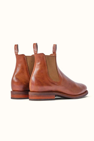 A pair of RM Williams Moriarty Rubber Sole Boots in brown pull-up leather featuring elastic side panels, a comfort insole, and pull tabs on the back. The almond toe design is showcased against a light background, viewed from a slight rear angle.