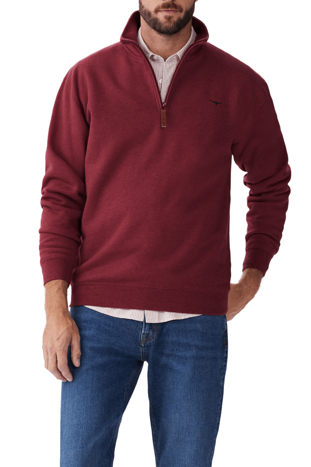 Someone wears an RM Williams Mulyungarie Fleece in maroon over a striped dress shirt and blue jeans. The fleece has a small embroidered logo on the chest, with one hand casually tucked in their pocket.
