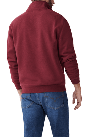 Wearing the RM Williams Mulyungarie Fleece in maroon and blue jeans, a person is shown from the back. Their left hand slightly raised and right hand relaxed at their side, the simple white background accentuates the cozy elegance of their fleece pullover.
