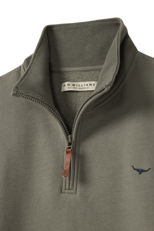 Close-up of an olive green RM Williams Mulyungarie Fleece quarter-zip sweatshirt featuring a stand-up collar, brown leather zipper pull, and small embroidered bull logo on the chest. The inside label reads “R.M. Williams.”.