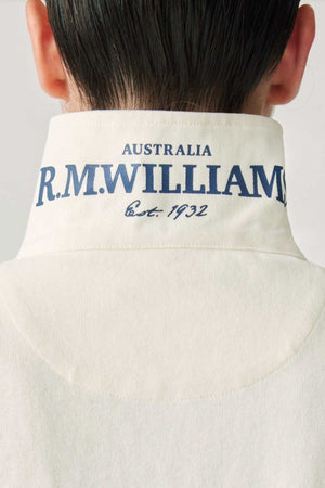 Close-up of the back of a person's neck wearing the RM Williams Narran Rugby shirt crafted from organic cotton, with the collar turned up. The collar features text that reads "R.M. Williams Australia Est. 1932" in blue lettering, showcasing the brand's heritage embroidery.