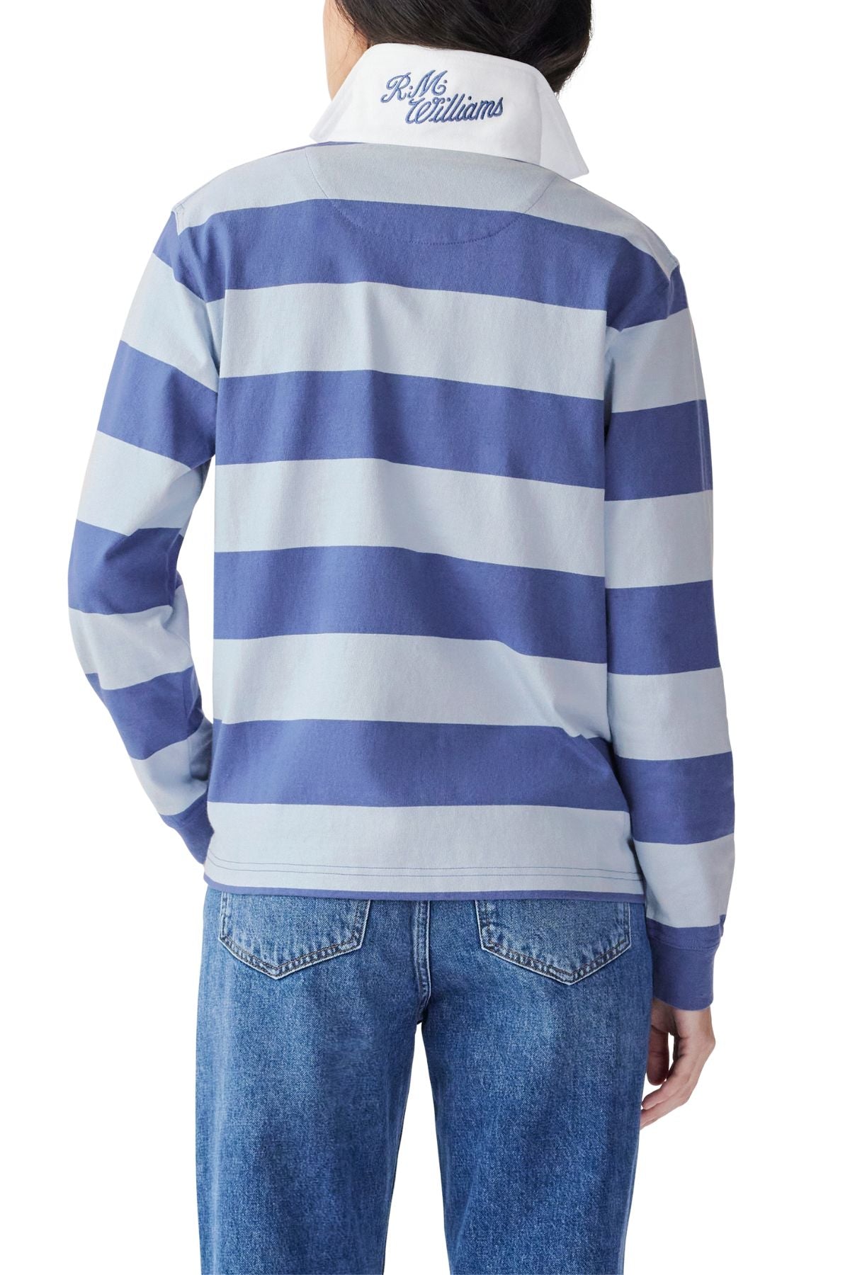 A person shown from the back against a white background wears blue jeans and the RM Williams Narran Stripe Rugby— a blue and white striped heavyweight organic cotton jersey with "P. M. Williams" embroidered on its brushed twill collar.