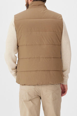 A person is shown from behind wearing the RM Williams Padstow Vest in tan, made from recycled nylon, over a light beige long-sleeve shirt and beige pants against a plain white background.