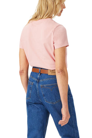 A woman with blonde hair, seen from the back against a white background, wears the RM Williams Piccadilly Tee in light pink with subtle longhorn embroidery, paired casually with blue jeans and a brown belt.