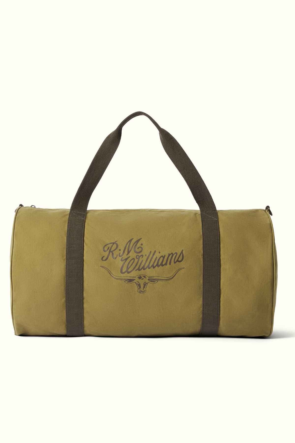 Displayed is the RM Williams RM Ditty Bag, a khaki green duffle constructed from Halley Stevensons waxed cotton canvas. It features dark green handles and prominently showcases the "R.M. Williams" logo at its center, making it a reliable travel companion.
