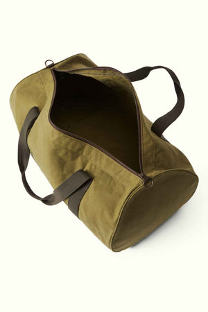 An RM Williams RM Ditty Bag, expertly crafted from Halley Stevensons waxed cotton canvas, sits with a partially open zipper that reveals its empty interior. This green duffel bag features dark green handles and a shoulder strap, making it the ideal travel companion against a plain light background.
