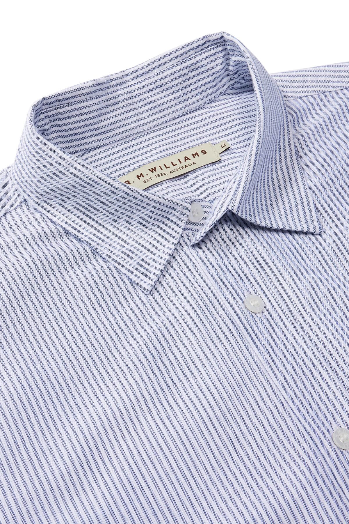 Close-up of a neatly folded RM Williams Regular Shirt in blue and white stripes, crafted from organic cotton. This slim fit button-up features a collar with a label at the collar area.