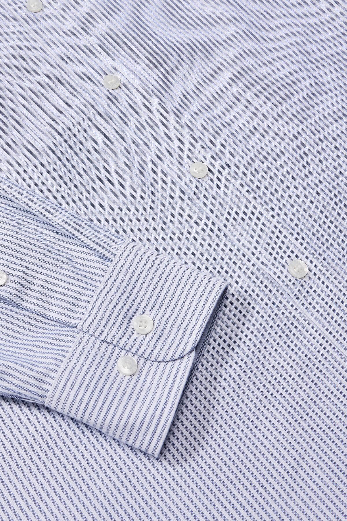 A close-up of the RM Williams Regular Shirt shows its blue and white striped design, buttoned cuff, organic cotton fabric with alternating thin lines, and white buttons.