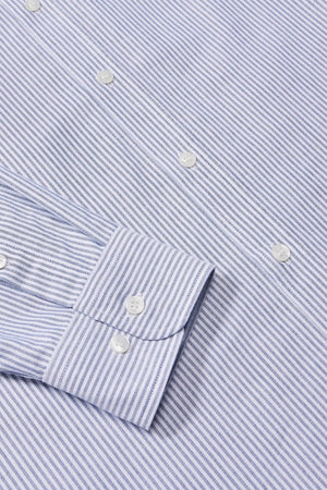 A close-up of the RM Williams Regular Shirt shows its blue and white striped design, buttoned cuff, organic cotton fabric with alternating thin lines, and white buttons.