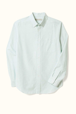 The RM Williams Regular Shirt, crafted from organic cotton, showcases a light green and white striped pattern with a classic collared design, long sleeves, and a front pocket. It features a button-down center and is displayed flat against a cream-colored background.