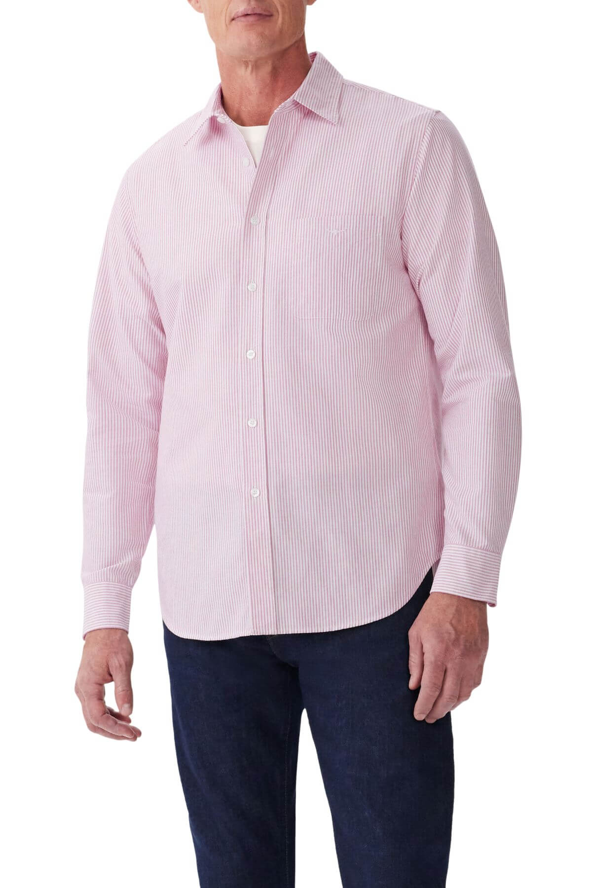 A man wears an RM Williams Regular Shirt in light pink and white stripes over a white undershirt, paired with dark blue jeans.