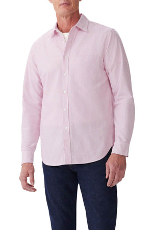 A man wears an RM Williams Regular Shirt in light pink and white stripes over a white undershirt, paired with dark blue jeans.